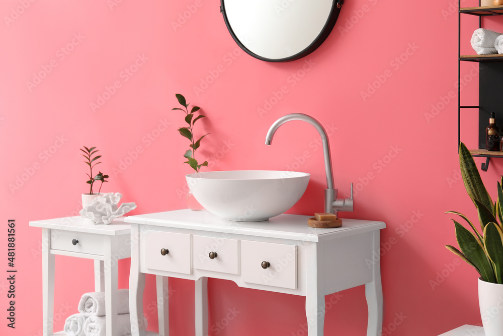 Table with sink, soap and plant branch in vase near pink wall