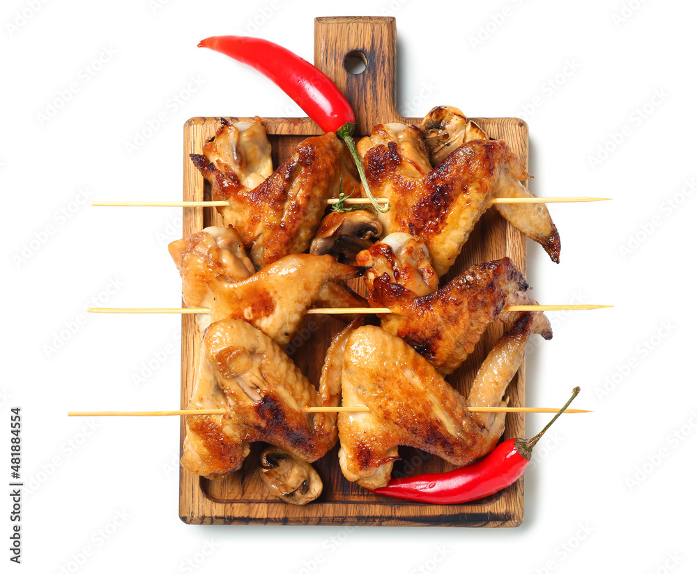 Wooden board with grilled chicken wings skewers on white background