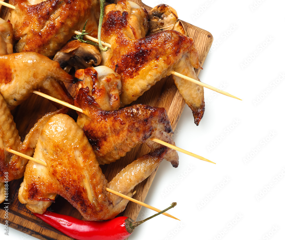 Wooden board with grilled chicken wings skewers on white background, closeup