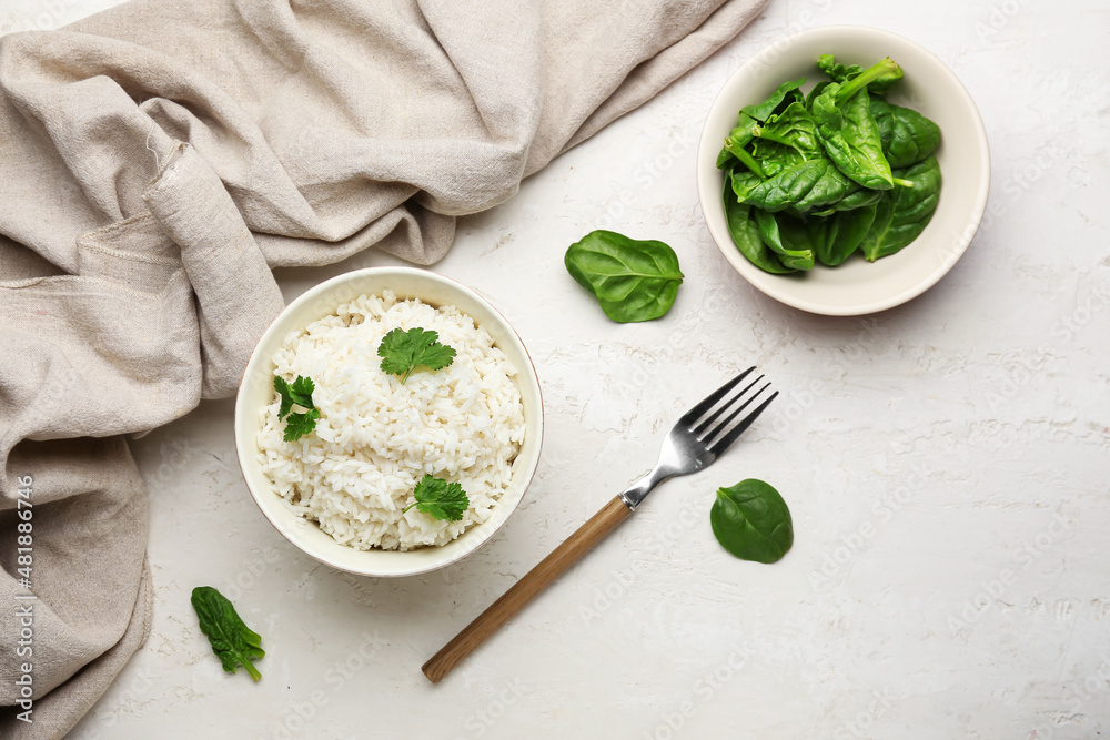 Bowl with tasty boiled rice and spinach on light background