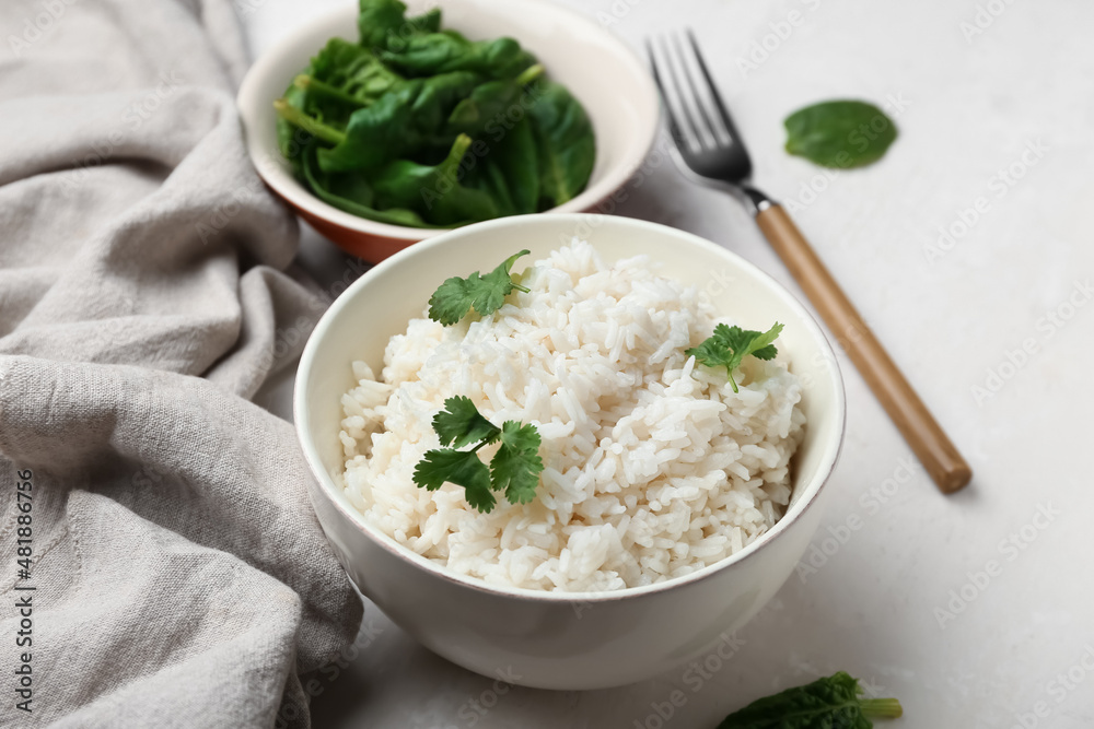 Bowl with tasty boiled rice and spinach on light background, closeup