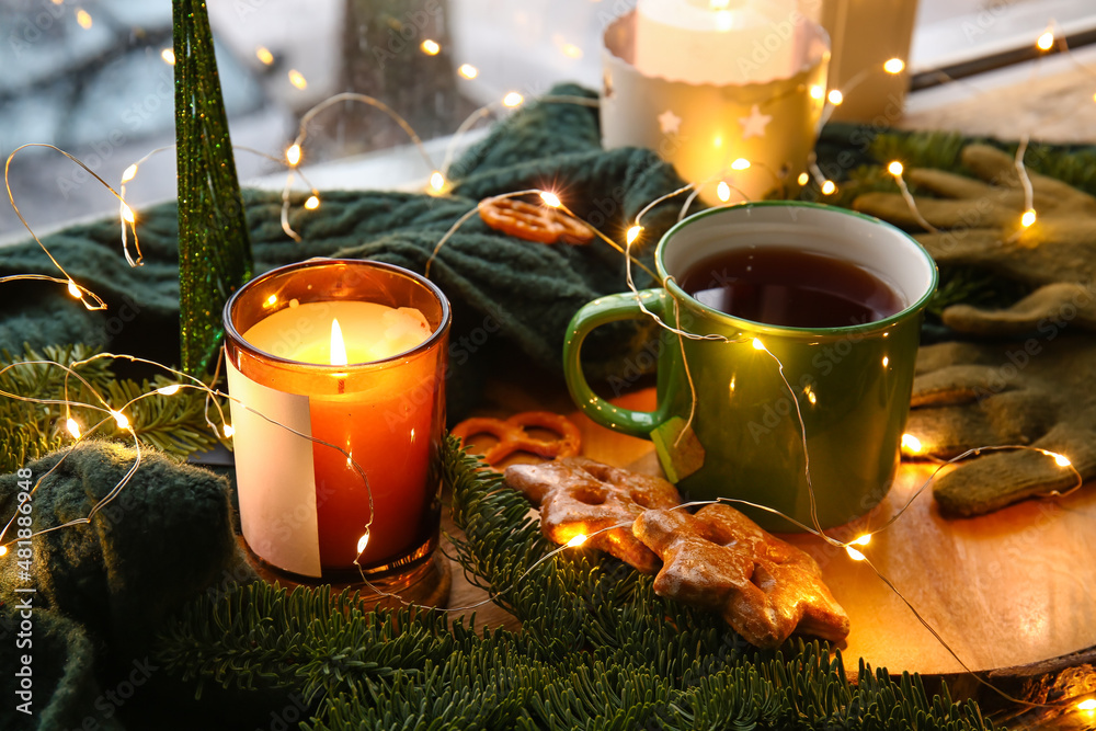 Cup of tea and burning candles on windowsill