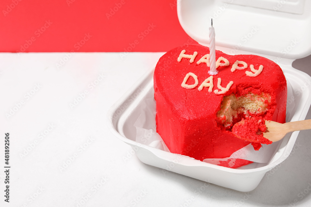 Plastic lunch box with tasty bento cake and candle on color background, closeup