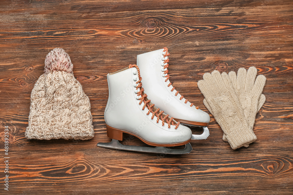 Ice skates with warm hat and gloves on wooden background