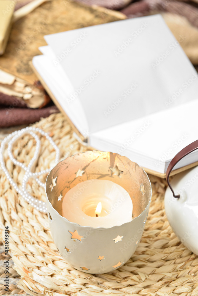 Beautiful burning candle on wicker mat