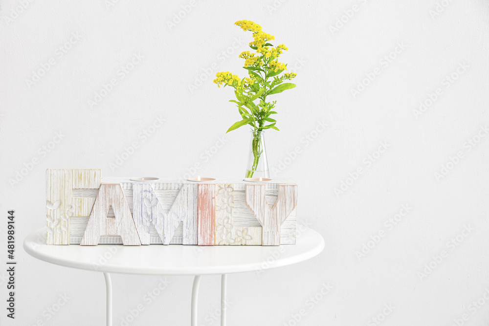 Candle holder in shape of word HOME and flowers on table