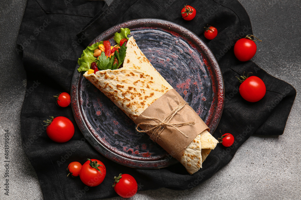 Plate with delicious burrito and tomatoes on grey background