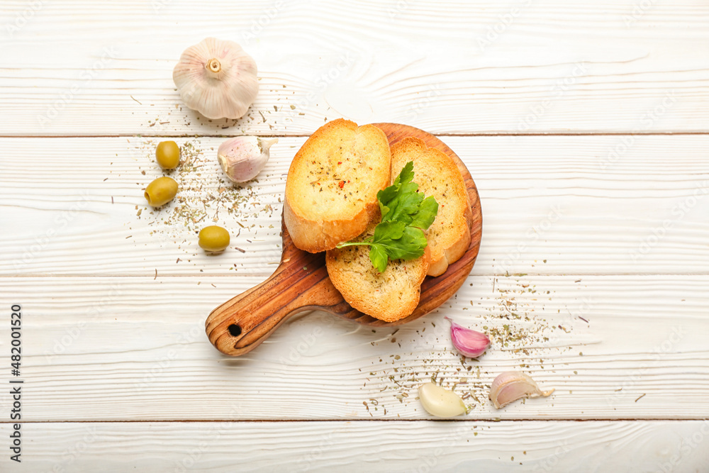 Board of tasty croutons on white wooden background