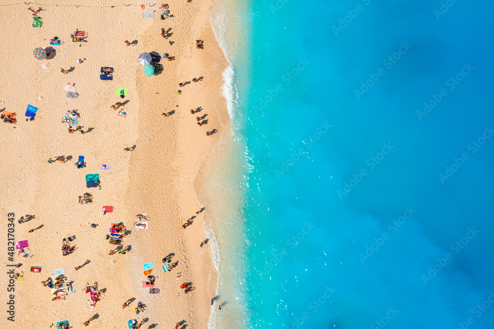 People relaxing on the beach during their vacation. Blue sea water. Summer landscape from drone. Aer