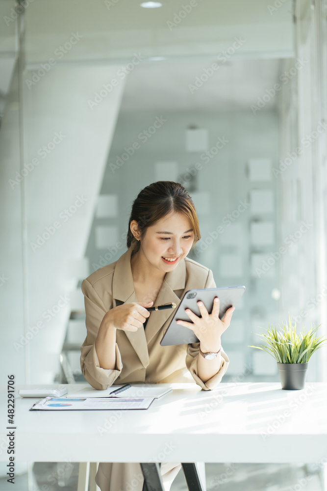 亚洲女性，坐在窗前使用数字平板电脑的魅力亚洲商业女性