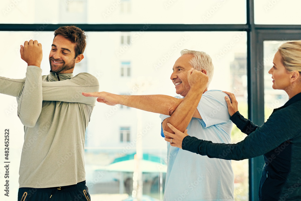 Helping him get it just right. Shot of two physiotherapists helping their senior patient with his ex