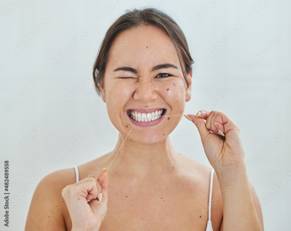 Keeping up with my dental hygiene. Shot of a young woman flossing her teeth in a bathrroom at home.