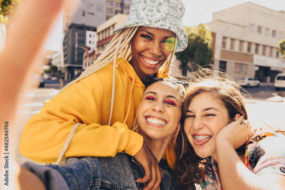 Trio of female friends taking a group selfie outdoors in the city