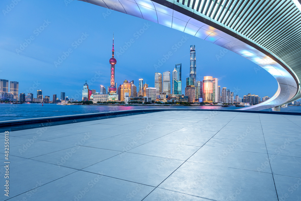 Panoramic skyline and modern commercial buildings with empty square floor in Shanghai at night, Chin