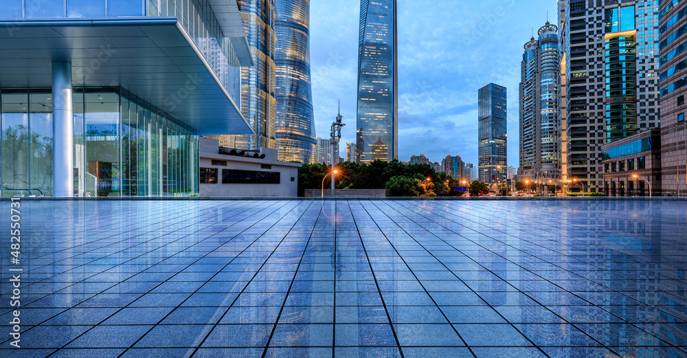 Empty square floor and city skyline with modern commercial buildings at night in Shanghai, China.