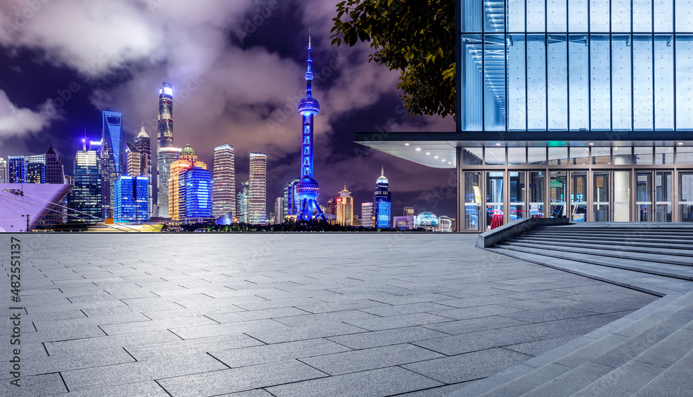 Panoramic skyline and modern commercial buildings with empty square floor in Shanghai at night, Chin