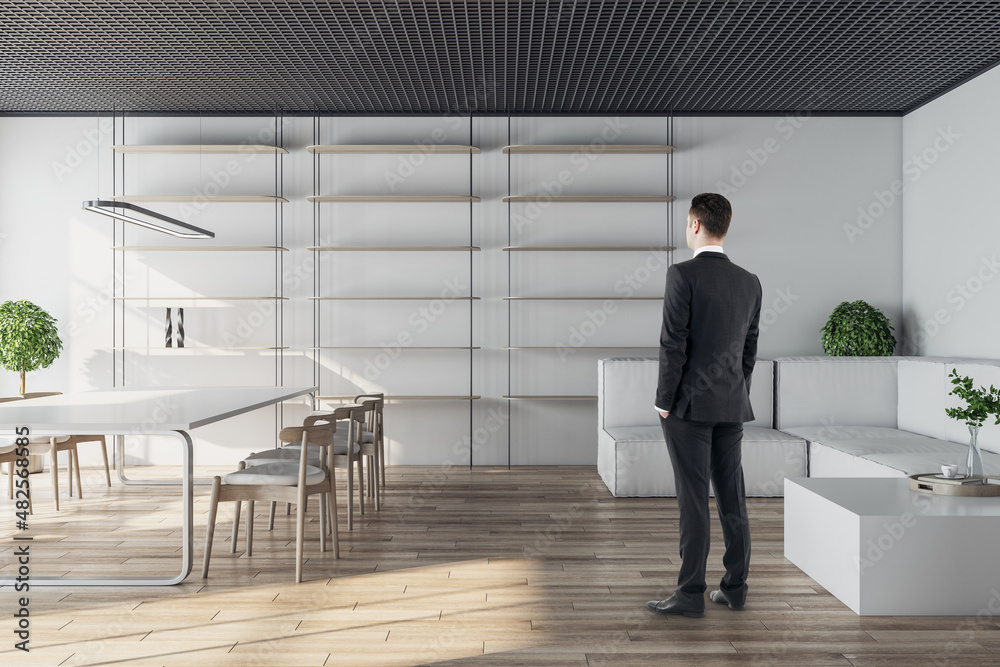 Businessman standing in modern conference room interior with glass partition, wooden flooring and da