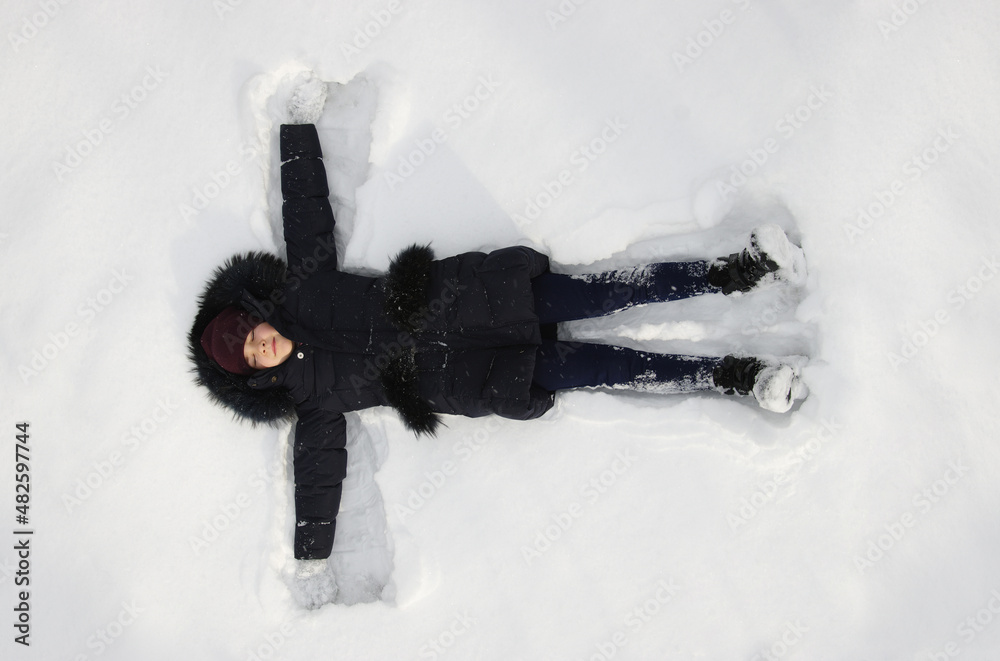 快乐的女孩冬天躺在雪地上