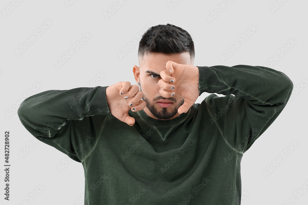 Young man with stylish manicure on light background