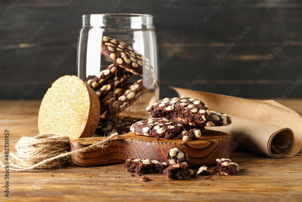 Wooden board of tasty cookies with white chocolate chips on table