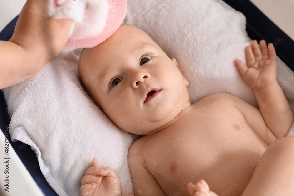 Mother washing her baby boy with sponge at home, closeup