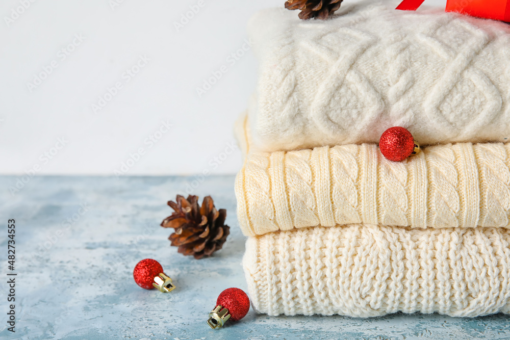 Stylish baby sweaters and Christmas decor on table, closeup