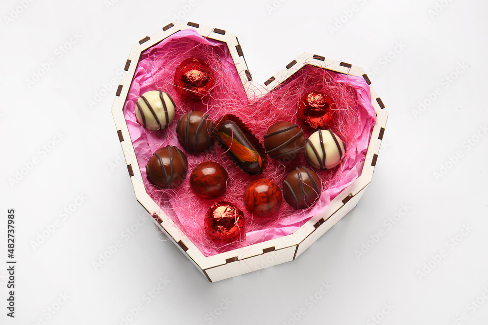 Heart shaped box with tasty chocolate candies isolated on white background