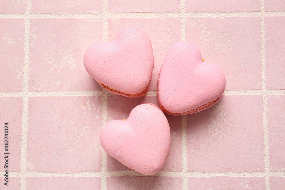 Tasty heart-shaped macaroons on pink background