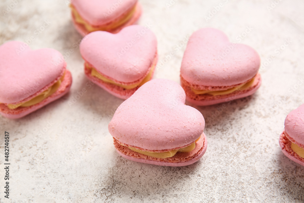 Tasty heart-shaped macaroons on light background