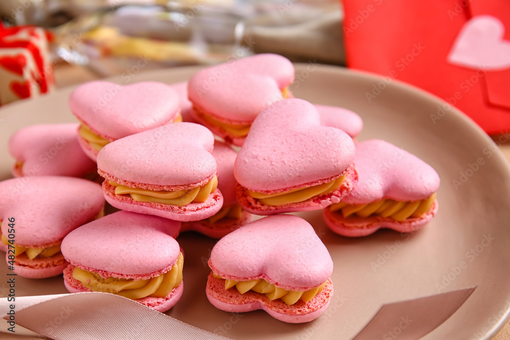 Plate with tasty heart shaped macaroons on table, closeup