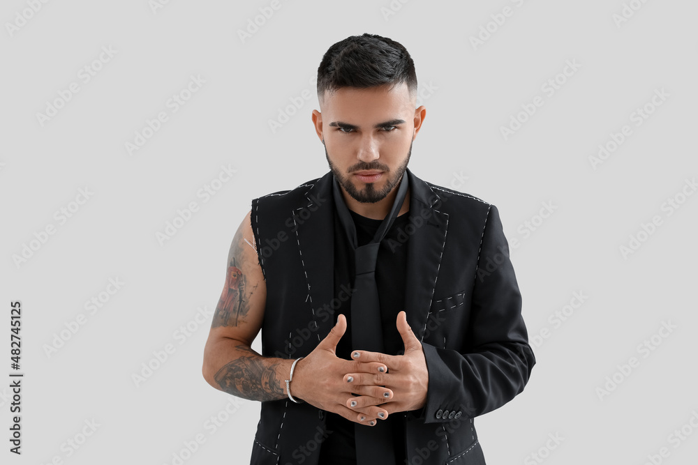 Man with stylish manicure and crossed fingers in unfinished suit on light background