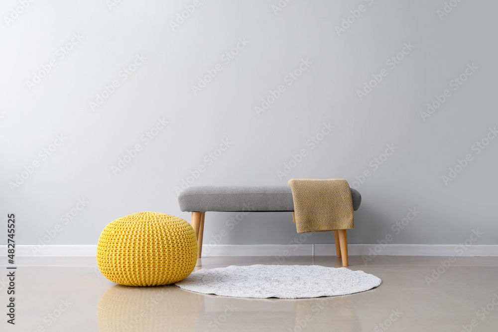 Comfortable pouf and bench with plaid near light wall