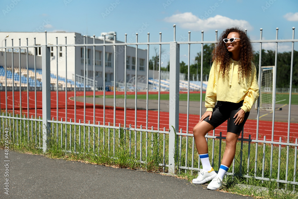 Beautiful young African-American woman in stylish hoodie outdoors