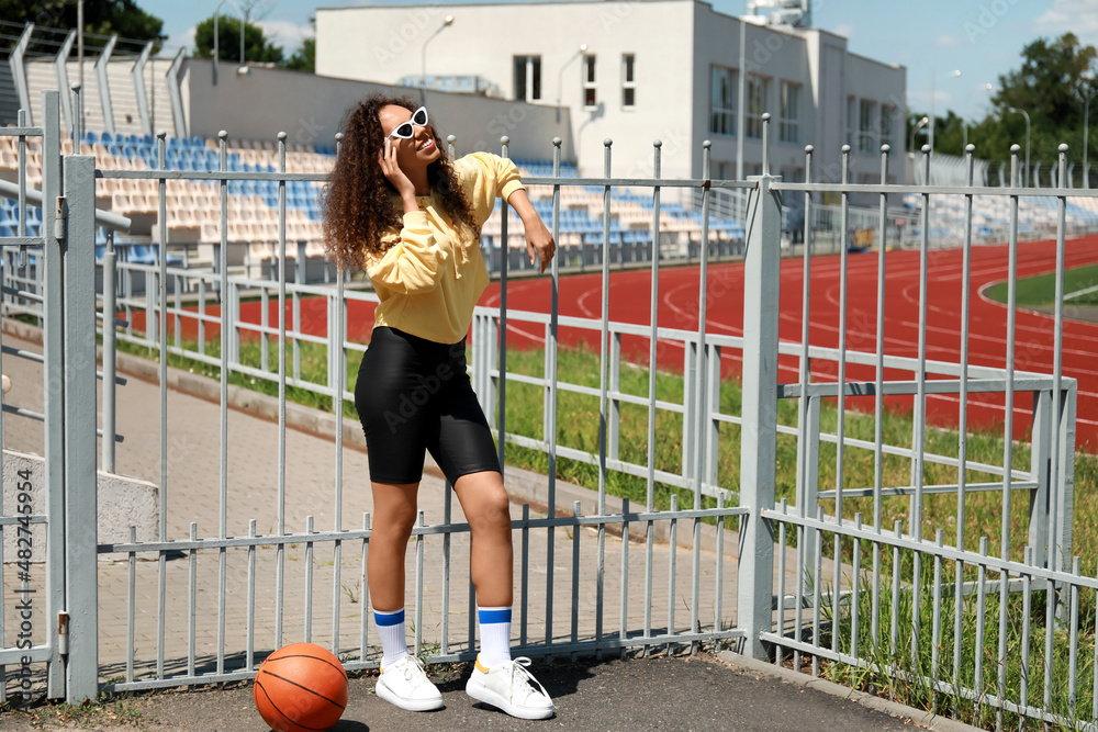 Beautiful young African-American woman in stylish hoodie outdoors