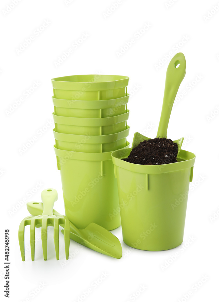 Flower pots with soil and gardening tools on white background