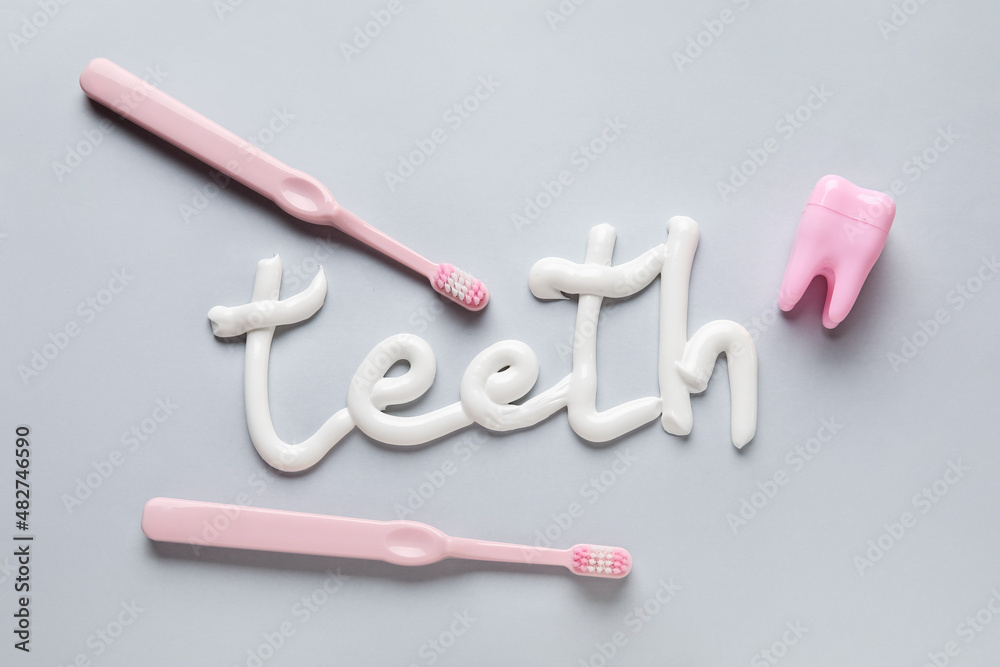 灰色背景下用牙膏写的牙刷、牙线和单词TEETH