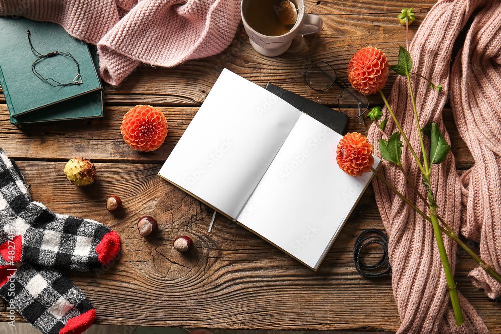 Blank book, cup of tea and flowers on wooden background