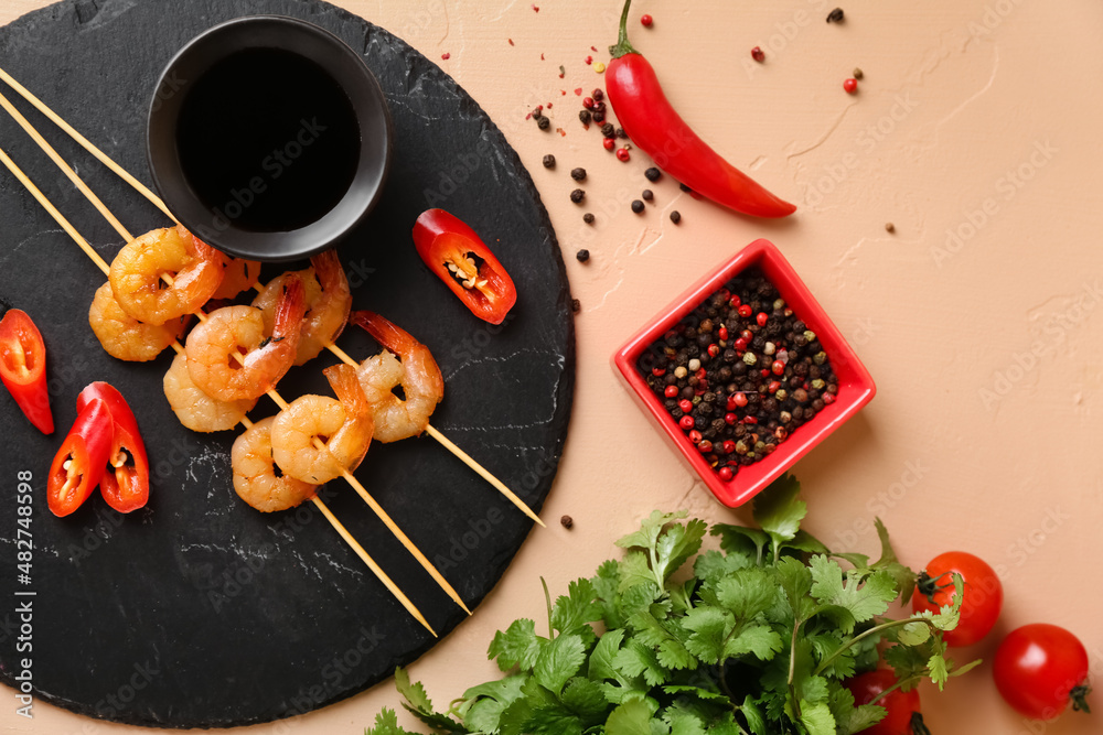 Board with grilled shrimp skewers and sauce on beige background