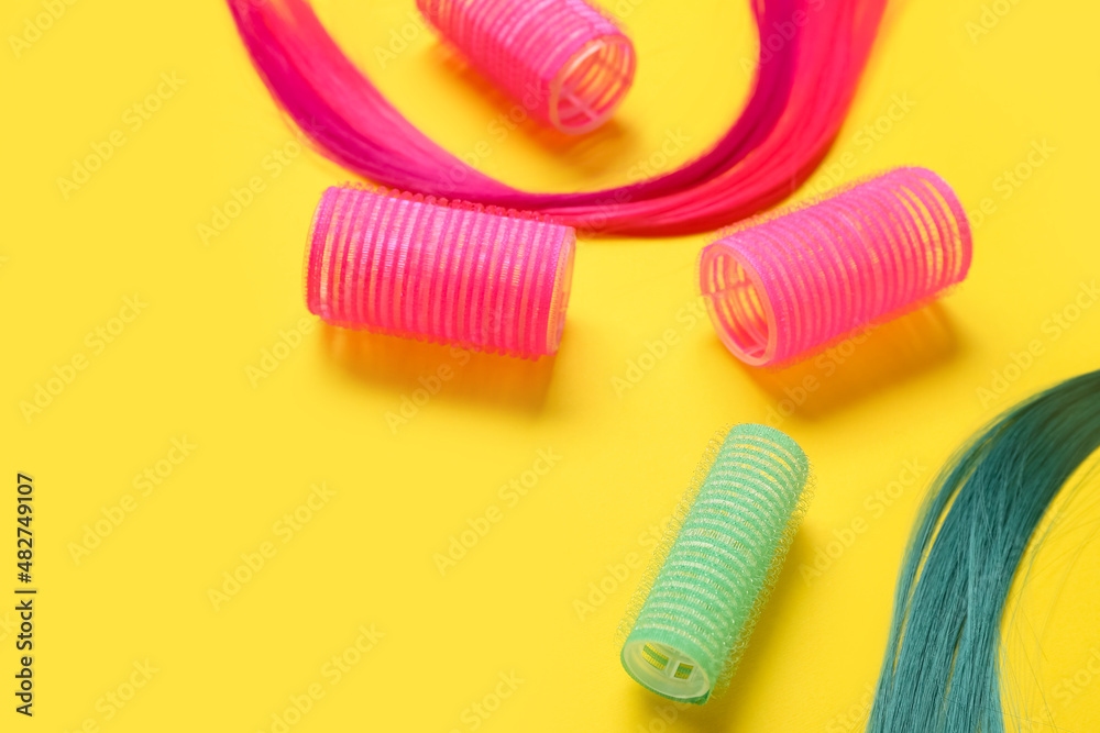 Strands of hair with curlers on color background, closeup