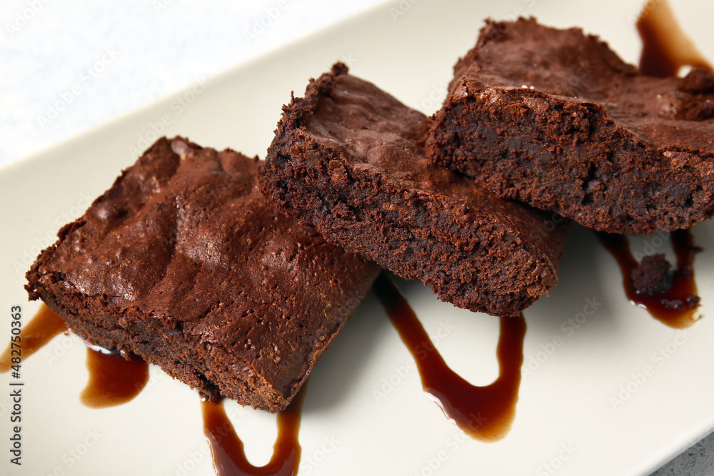 Plate with pieces of tasty chocolate brownie on table, closeup