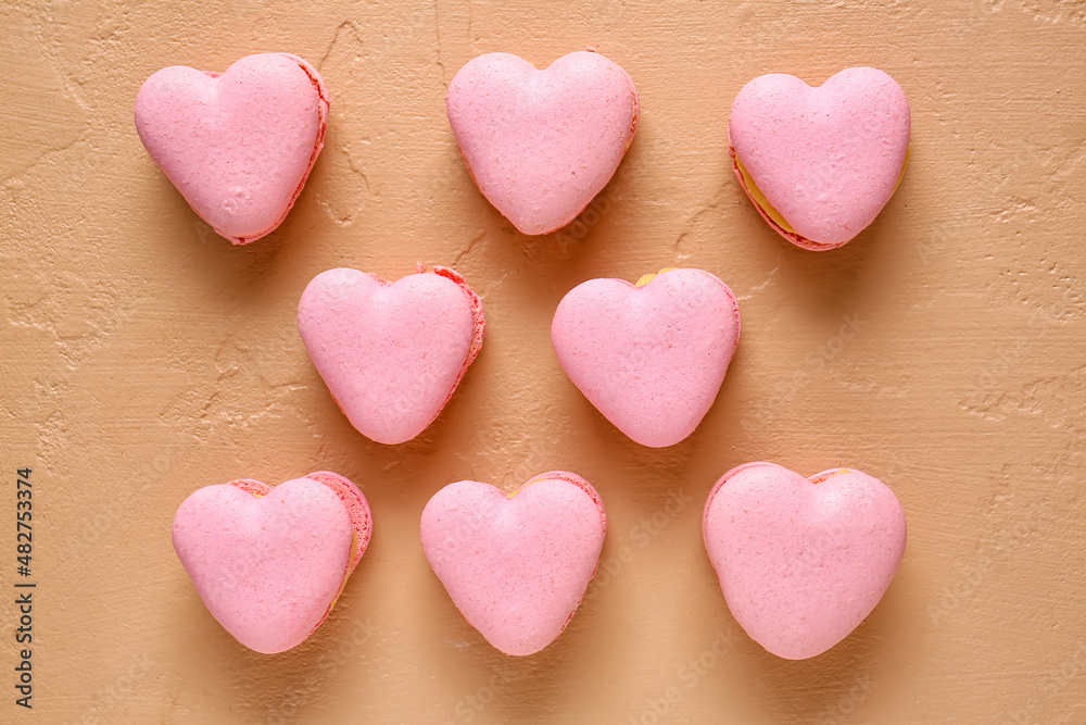 Tasty heart-shaped macaroons on beige background