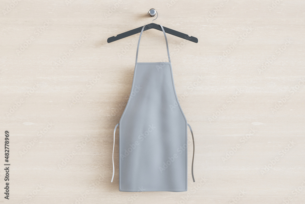 Empty gray kitchen apron on hangers. Light wood background. Chef and cooking concept. Mock up place.