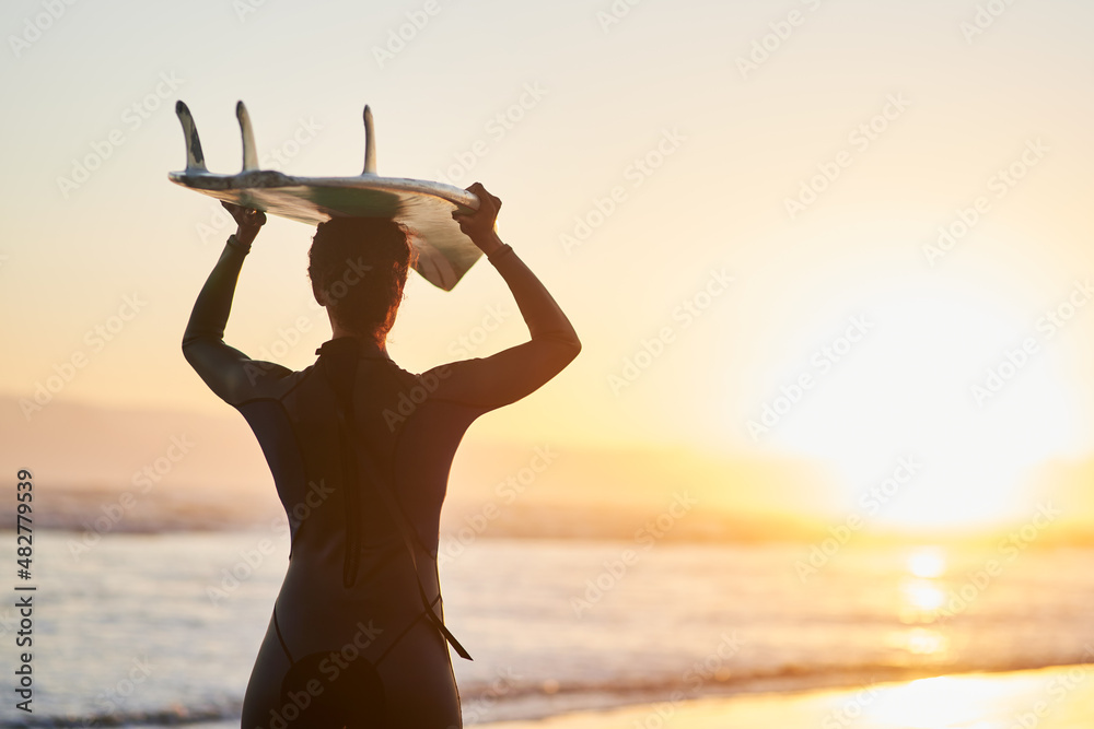 冲浪是一种生活方式。一名女冲浪者在t时将冲浪板举过头顶的后视镜头