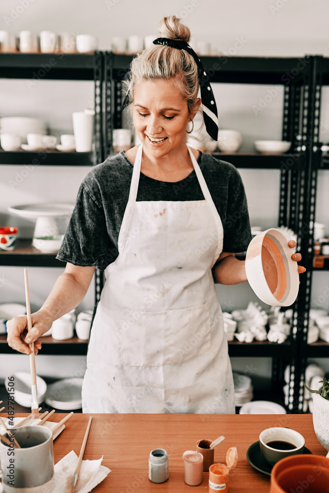 I love painting my pottery. Cropped shot of an attractive mature woman standing alone and painting a