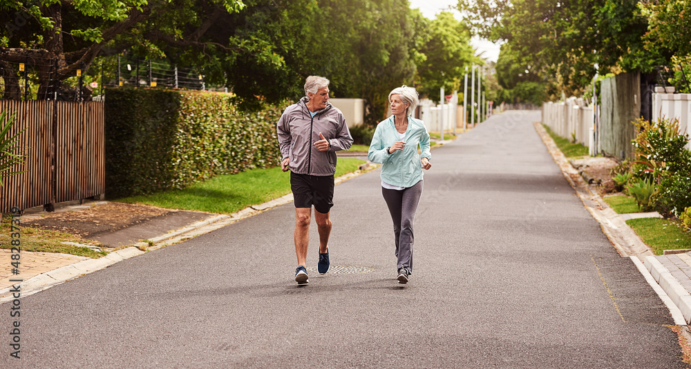 Try and keep up. Shot of a cheerful senior couple having a jog together outside in a suburb.