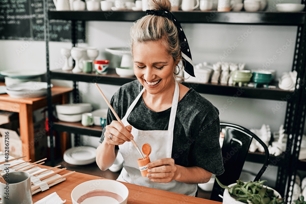 I love this colour. Cropped shot of an attractive mature woman sitting alone and painting a pottery 