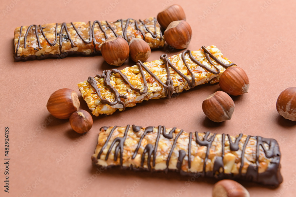 Tasty chocolate nut bars on color background