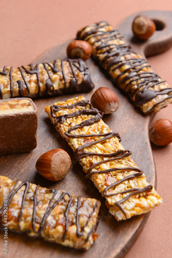 Board with tasty chocolate nut bars on color background