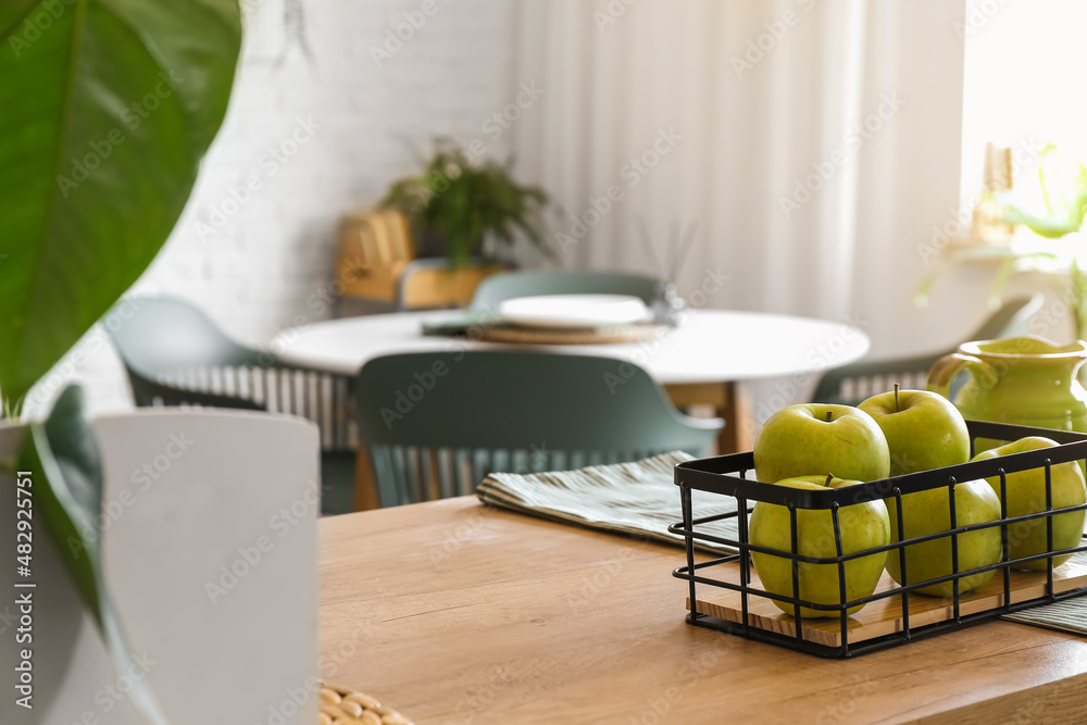 Basket with fresh apples on table in kitchen