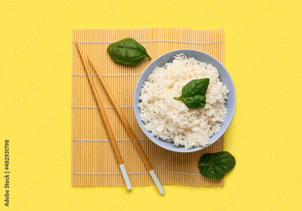 碗里有美味的煮米饭、菠菜和黄底筷子